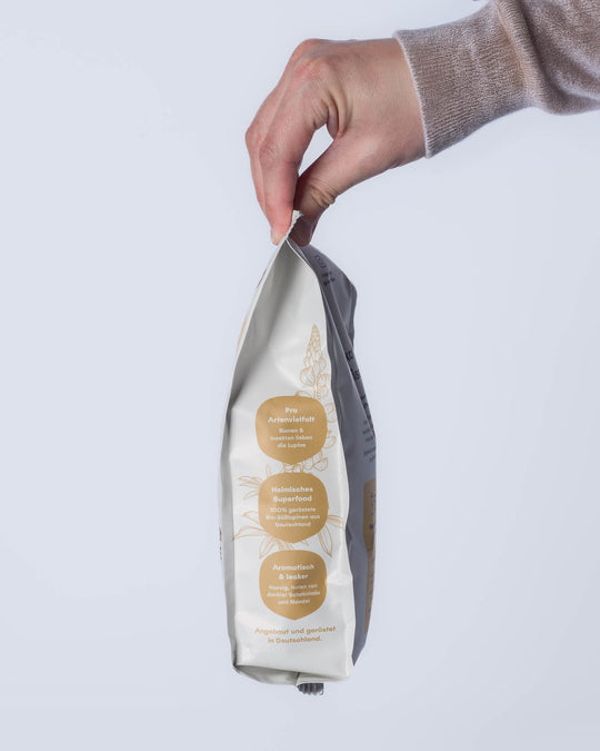 Tüte wird gehalten von einer Hand mit Pulli